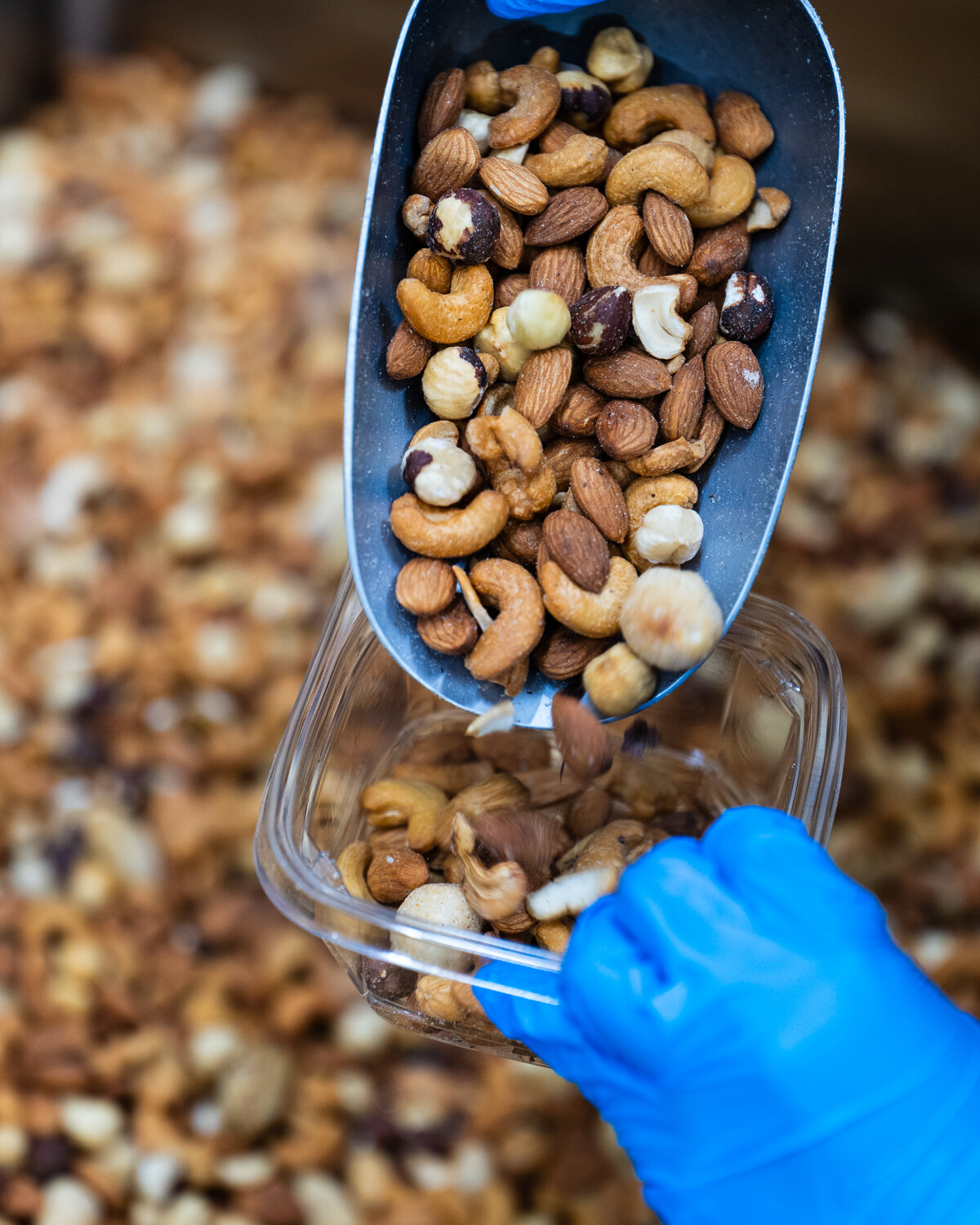A scoop of mixed nuts going into a tub.