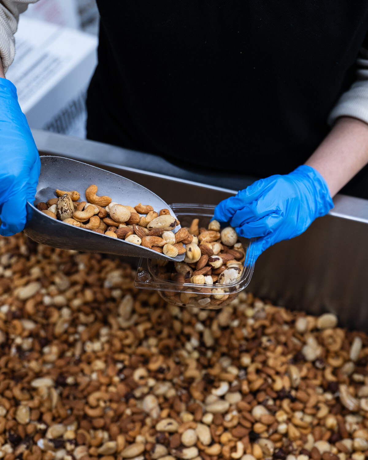 Nuts being scooped into a tub by hand in our packing room.