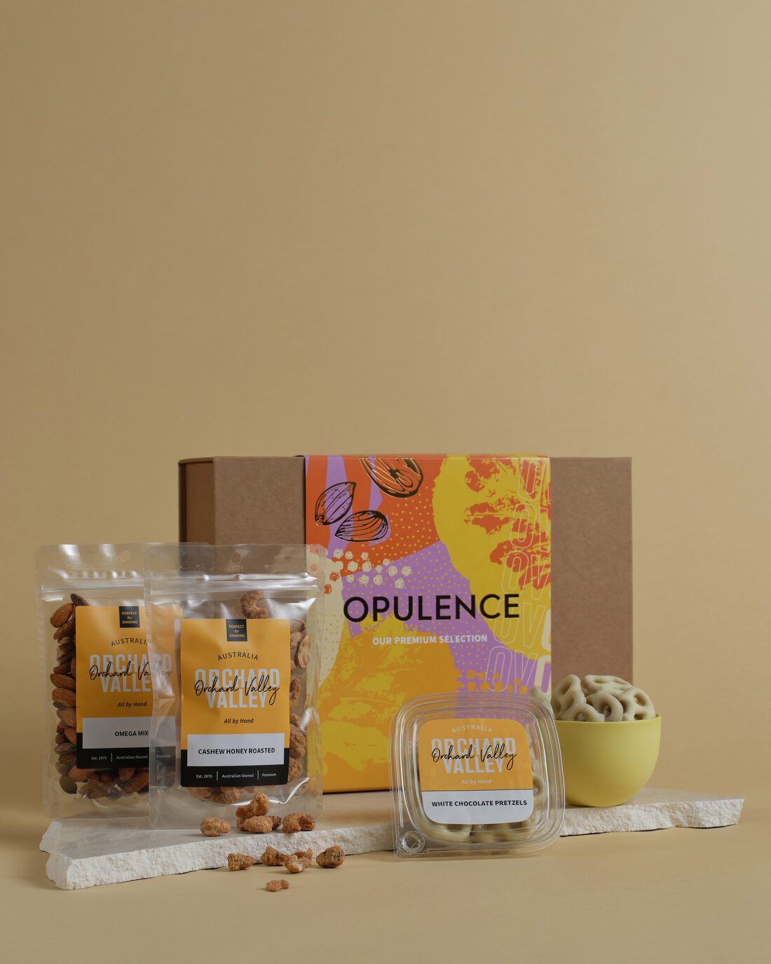 An Orchard Valley Opulence gift box with packets and a tub of nuts and chocolate.